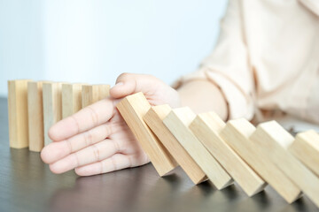 Woman hand stop wooden blocks for protect other wooden block, Concept Risk of management and strategy plan