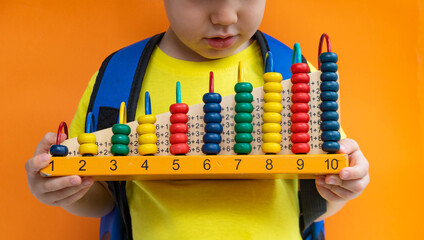 Preschooler school student child holding abacus over yellow orange background. Mental arithmetic...