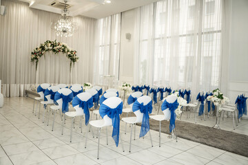 Bright room for weddings. Rows of guest chairs decorated with blue cloth