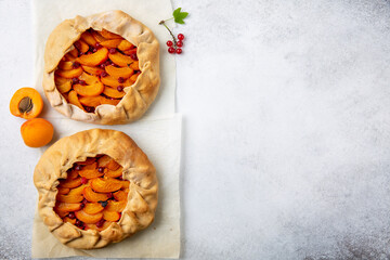 Fruit galette on light background. Homemade open pie with apricots and red currant. Top view, copy space.