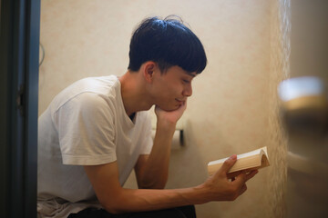 トイレで読書する男性