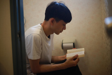 トイレで読書する男性