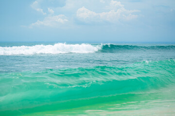 Fototapeta premium An ideal tropical sandy beach for surfing on the ocean. Beautiful clear turquoise water and waves.