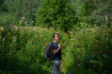 girl with a backpack in a meadow among large flowers