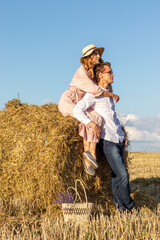 Outdoor portrait of couple in love sitting on hay bale.