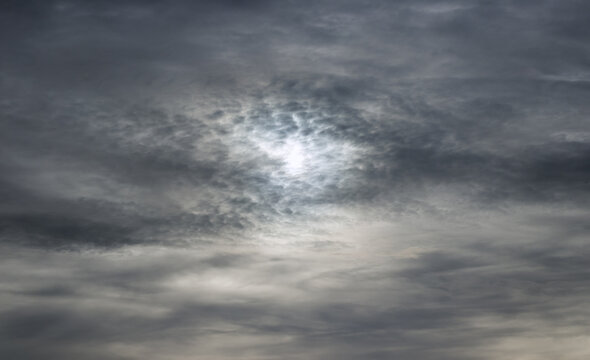 Sun through stormy clouds. Horizontal photo of majestic gray sky with sun over horizon. No birds, no noise.