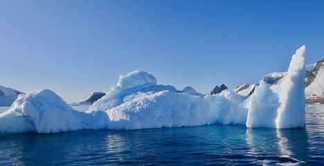 Blue iceberg in antarctic ocean, blue sky, bright sun, melting ice, Antarctica
