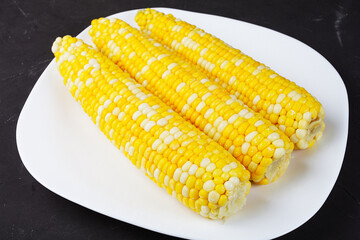 boiled corn on a white square plate, close-up, soft focus