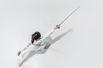 Champion. Teen girl in fencing costume with sword in hand on white background. Top view. Young...