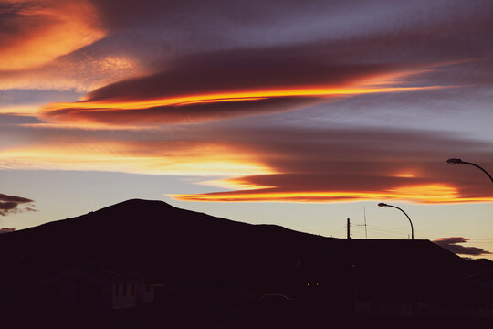Peaceful landscape of sunset with the silhouette of a small hill and beautiful yellow and purple clouds in the sky in Patagonia, Chile. Space for text.