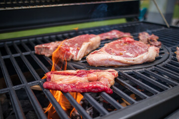 Home barbecue with charcoal in the backyard grilling steaks and other meats for carnivore diet.