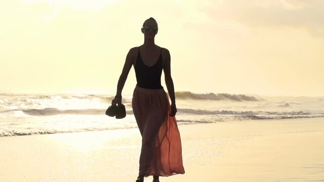 Beautiful young woman walking on beach