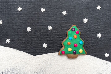 Lebkuchen Weihnachtsbaum im Schnee mit Schneeflocken auf schwarzem Hintergrund