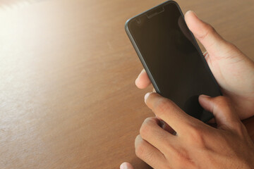 men's hands are holding a smartphone on the desk