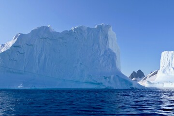 Blue iceberg in antarctic ocean, blue sky and sun, melting ice, Antarctica