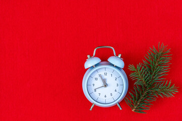 Christmas tree branches and blue retro alarm clock on red background, good for Christmas background