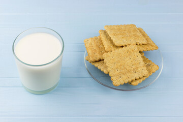 Fototapeta na wymiar glass of milk and a plate of cookies on a blue background