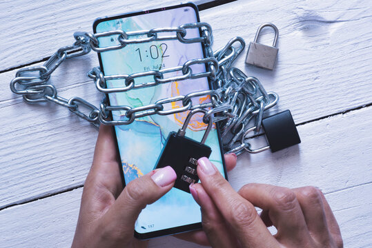 Smartphone addiction concept with mobile device in woman hands with chains and locker
