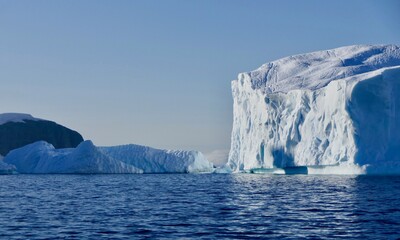 Fototapeta na wymiar Blue iceberg in antarctic ocean, blue sky and sun, melting ice, Antarctica
