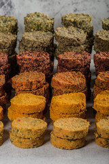 Breaded raw vegetables cutlets for vegan burgers on white paper. Toss the veggie stacked patties fresh breaded chops. Light white wooden background. Top view.