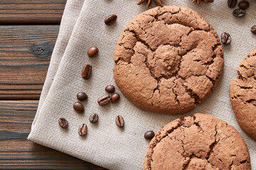 Top view of cookies and coffee beans on brown napkin and on wooden background. Closeup