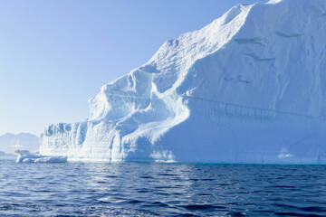 Iceberg in antarctic ocean, blue sky and sun, melting ice, Antarctica