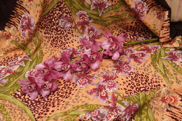 Fresh orchid flower lies on vintage folk russian Pavlovo Posad shawl, scarf with painted orchid...