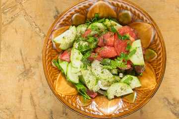 Top view on ceramic bowl full of vegan salad with red tomotoes, cucumbers, mangold , parsley  standing on a dirty wooden surface