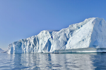 Edge of iceberg in antarctic ocean, blue sky and sun, melting ice, Antarctica