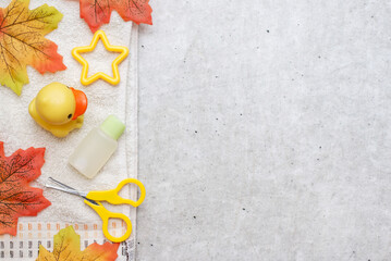 Flat lay natural baby bath products. Autumn leaves with body care accessories for child on grey background, copy space