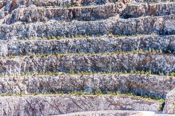 Aerial view of opencast mining quarry with one machinery on the blue sea background
