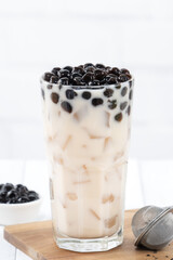 Bubble milk tea with tapioca pearl topping, famous Taiwanese drink on white wooden table background in drinking glass, close up, copy space