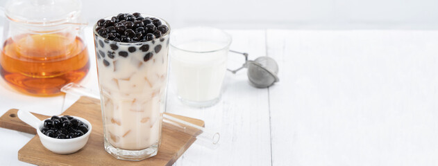 Bubble milk tea with tapioca pearl topping, famous Taiwanese drink on white wooden table background in drinking glass, close up, copy space