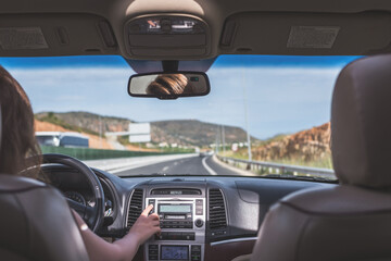 Fototapeta premium The girl is driving on the road on Tenerife, Canary Islands. View from the back seat of the car on the windshield, road and the driver