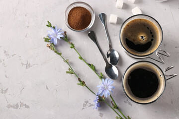 Chicory beverage in two glass cups, with concentrate and flowers on grey background. Healthy herbal beverage, coffee substitute, Close up, Copy space