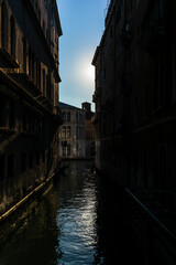 A lonely gondola navigating the water channeat sunrise near San Marco in the center of Venice