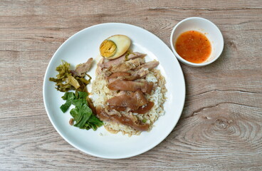 boiled pork leg slice in black Chinese herb soup with egg dipping spicy and sour chili sauce topping rice on plate