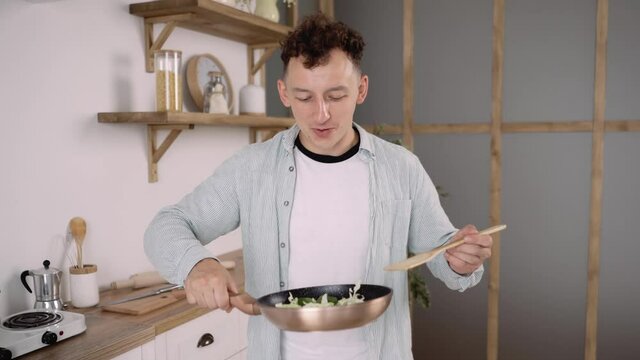 Close up of Young Good looking Man Cooking Happily in the Kitchen. Amateur Male Chef Recording Video Recipe or a Cooking Lesson for a Blog.