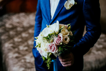 the groom holds the bride's bouquet, the wedding bouquet on the background of the jacket, the...