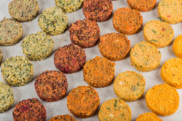Breaded raw vegetables cutlets for vegan burgers on white paper. Toss the veggie stacked patties fresh breaded chops. Light white wooden background. Top view.