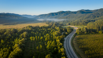 Idyllic landscape shot from above in early morning sunlight, meadows and forests with blue sky and...