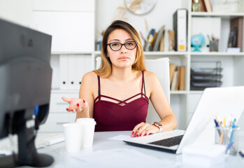 Young colombian woman in glasses working with laptop at the office table