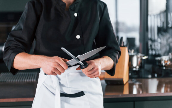 Professional young chef cook in uniform standing and preparing for the work on kitchen