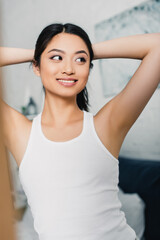 Fototapeta na wymiar Selective focus of cheerful asian girl looking away in bedroom