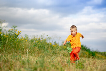 Naklejka na ściany i meble happy baby boy running across the field in summer, a child's lifestyle