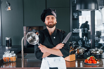 Portrait of professional young chef cook in uniform that posing for camera on the kitchen