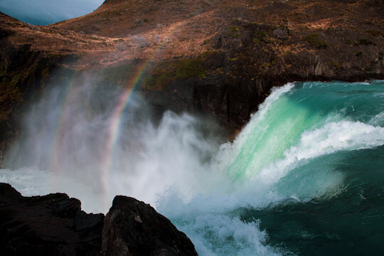 Scenic view of rainbow over waterfall flowing through rocks