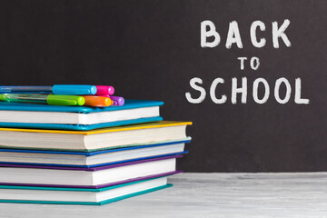 The concept of going back to school. School supplies with books, pens on the background of the Board. Chalk back to school