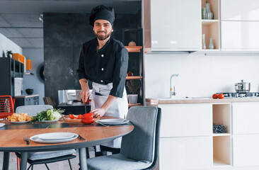 Professional young chef cook in uniform making salad on the kitchen