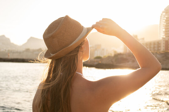Chica adolescente rubia cogiendo su sombrero al atardecer en la playa de Calpe